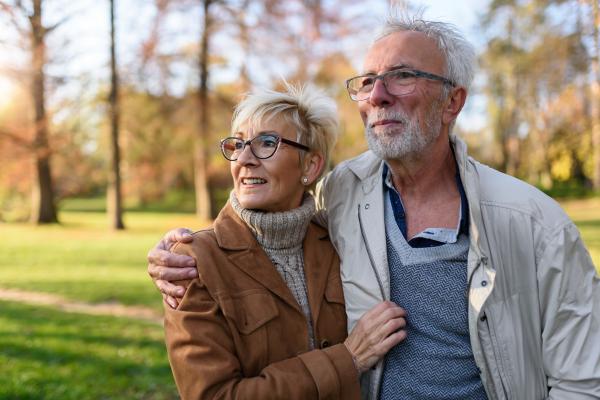 Mature couple smiling and walking outside together, healthy because they've had their RSV vaccine