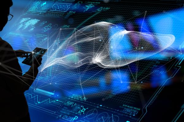 Silhouette of a person operating a tablet compouter in front a digital projection of liver imagery