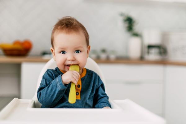 Baby with yellow spoon in mouth