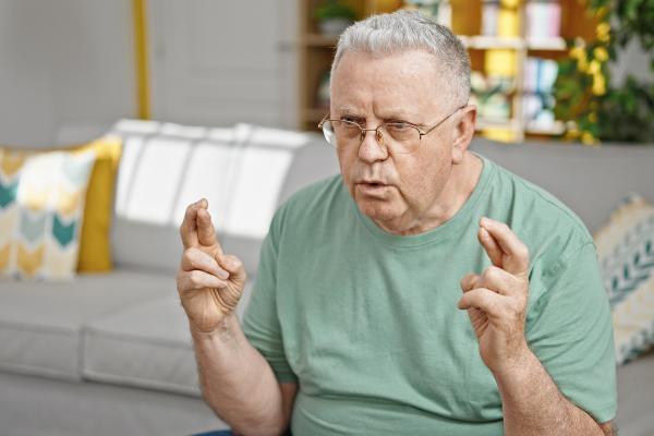 older man with fingers on both hands crossed