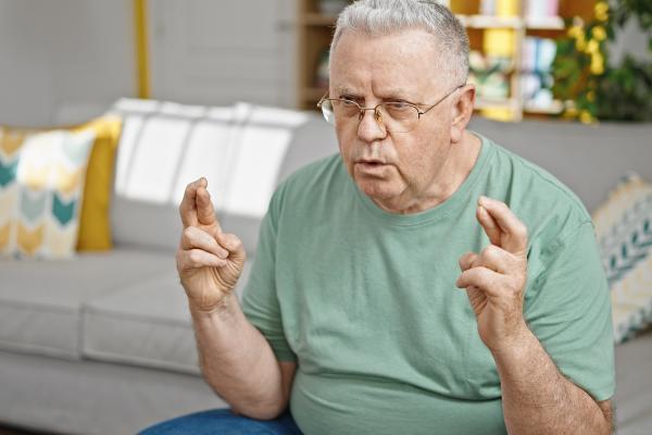 older man with fingers on both hands crossed