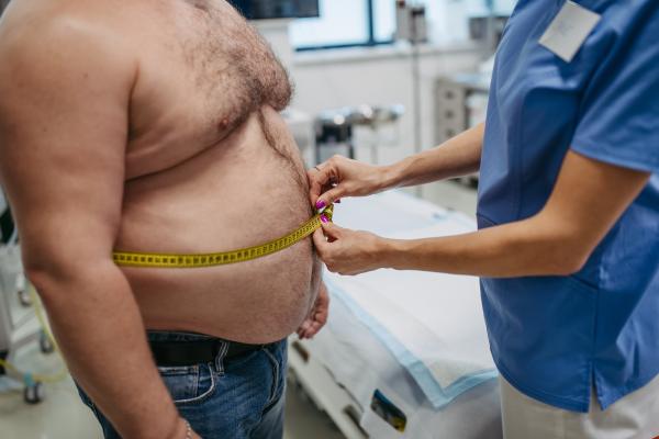 Obese man having his waist circumference measured