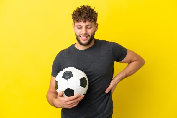 man with a soccer ball experiencing back pain