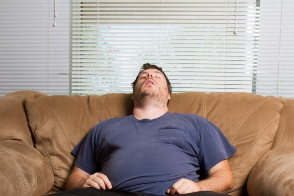 Obese man asleep on the lounge