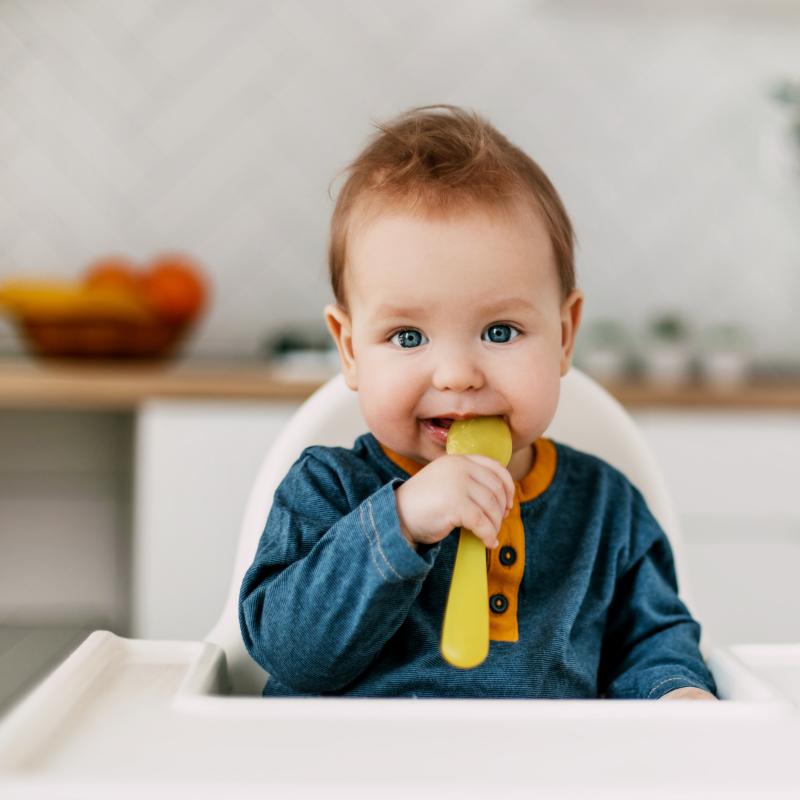 Baby with yellow spoon in mouth