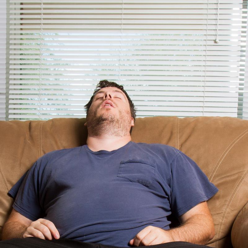 Obese man asleep on the lounge