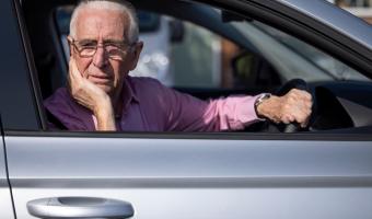 Senior male driving looking worried and confused