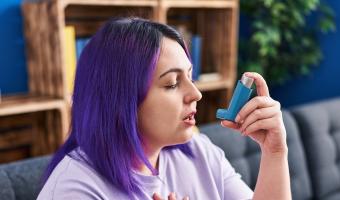 middle aged overweight woman with purple hair using an inhaler