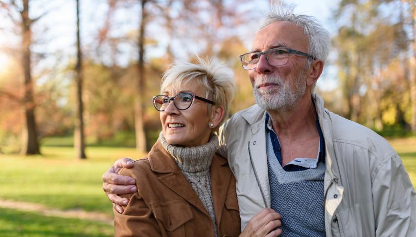 Mature couple smiling and walking outside together, healthy because they've had their RSV vaccine