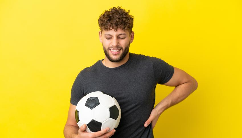 man with a soccer ball experiencing back pain
