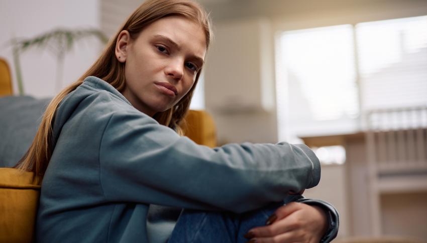 young lady sitting on the floor looking directly at the camera