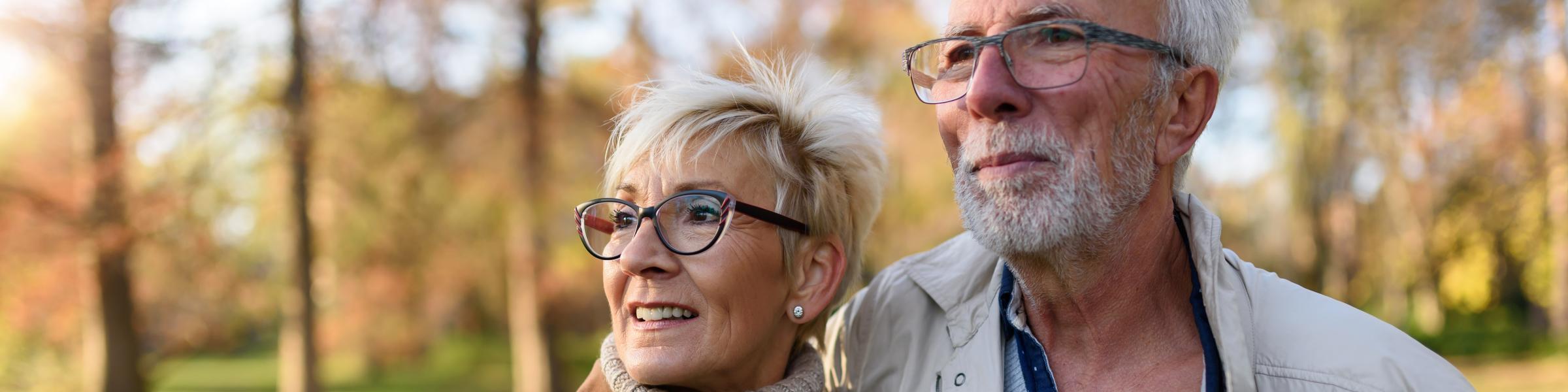 Mature couple smiling and walking outside together, healthy because they've had their RSV vaccine