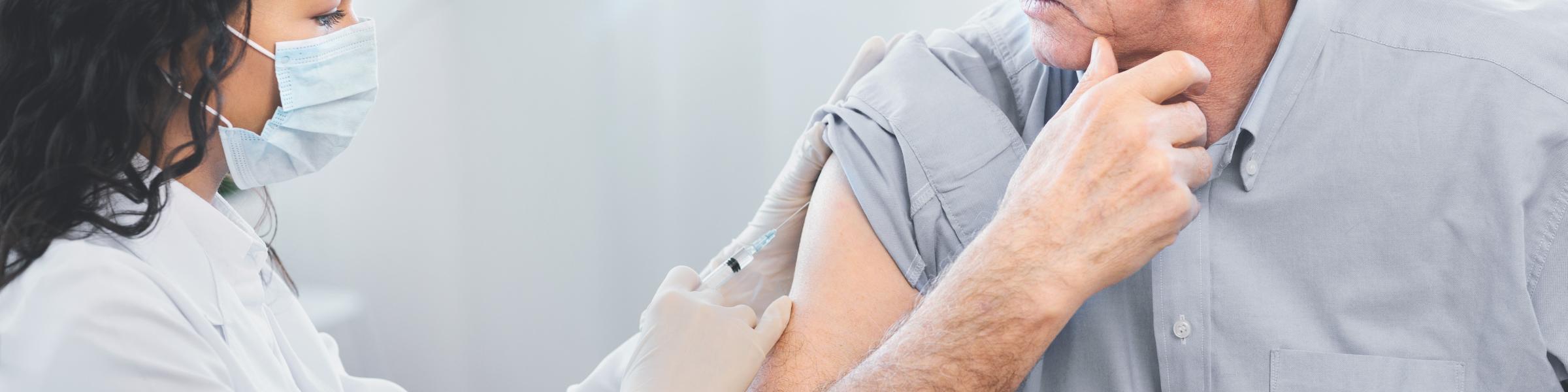 Nurse giving imunisation injection to older male patient