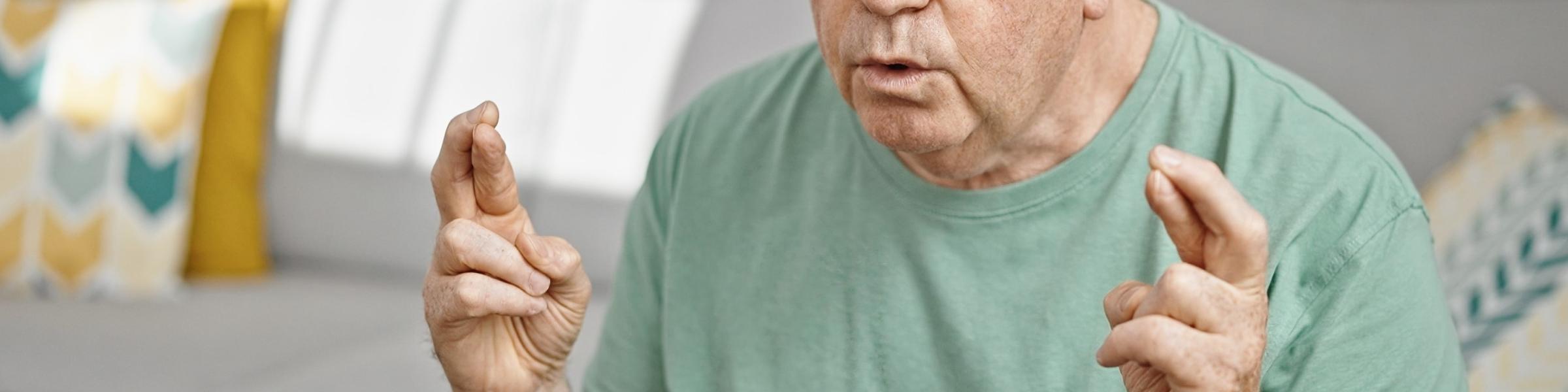 older man with fingers on both hands crossed