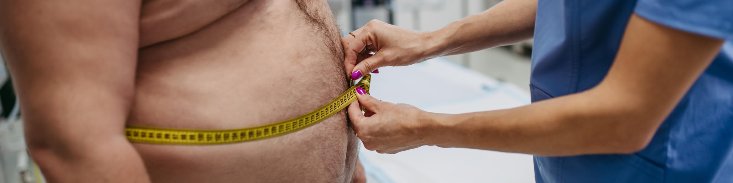 Obese man having his waist circumference measured