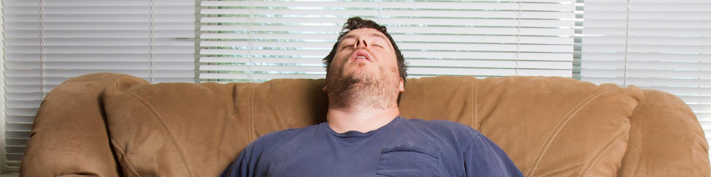 Obese man asleep on the lounge
